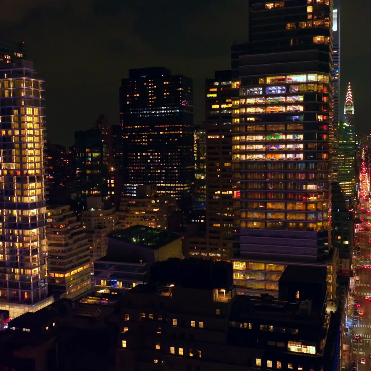Flying among the skyscrapers of Midtown Chicago. Beautiful contemporary buildings with lights in windows at night time. Aerial view
