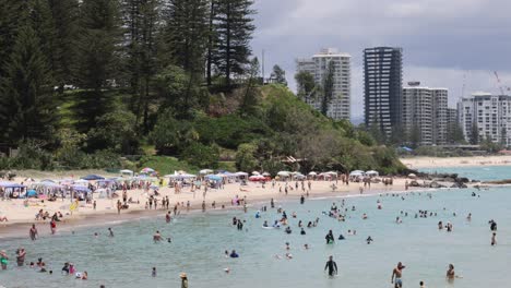 crowded beach scenes with city skyline in background