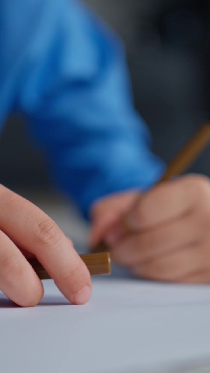 Ragazzo concentrato che disegna con una matita su carta bianca