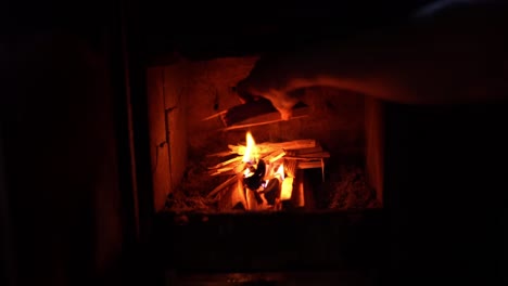 person putting wood log over fireplace. close up