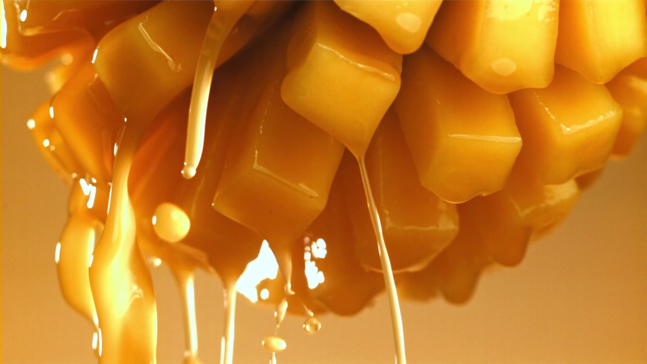 Sciroppo dorato che cola su mango fresco a cubetti al rallentatore