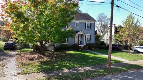 blue colored american single family house with halloween pumpkin in entrance. aerial approaching shot. suburb district of american village in autumn season.