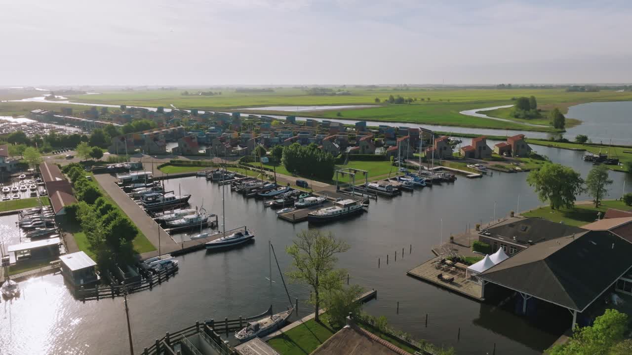 Drone makes a semi orbit revealing residential canals and moored boats in Heeg under soft daylight