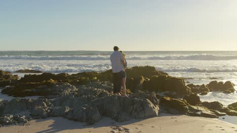 Couple-standing-on-rocky-shore-at-beach-4k