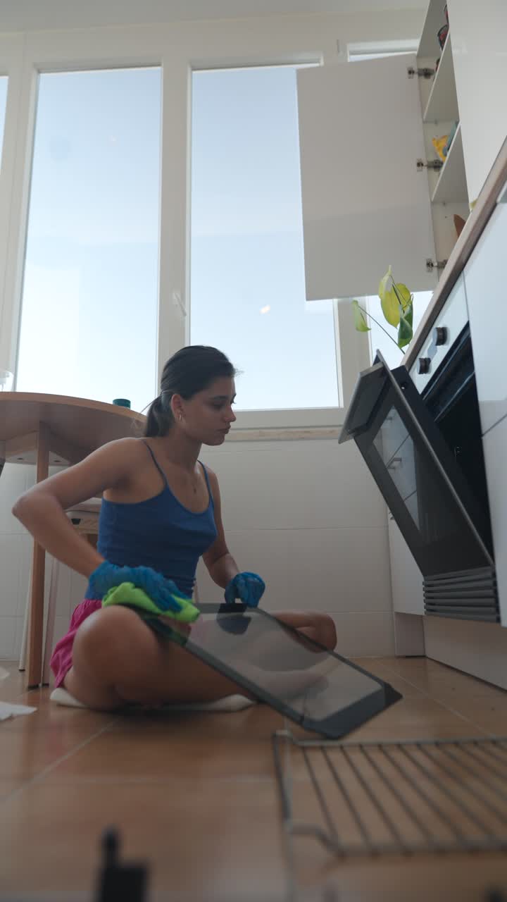 mujer limpiando el horno en la cocina