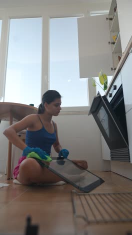 mujer limpiando el horno en la cocina