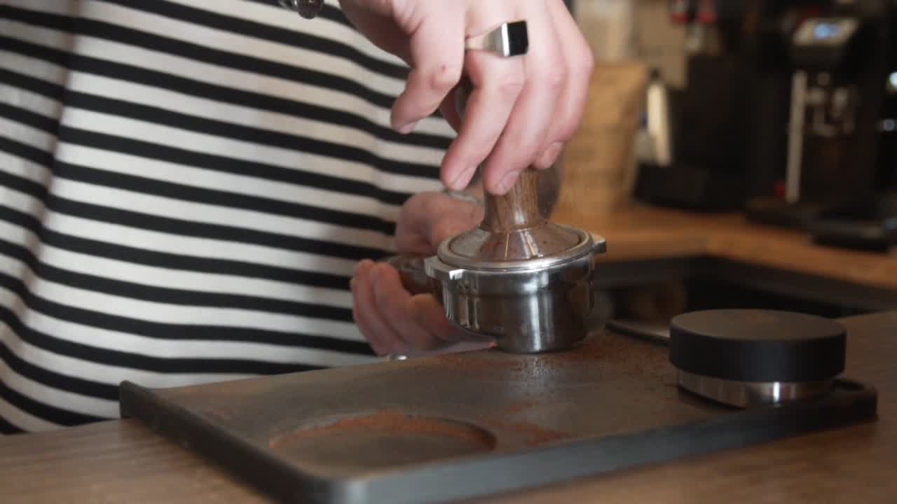barista profesional usando un sabotaje para presionar el café molido en el portafiltro