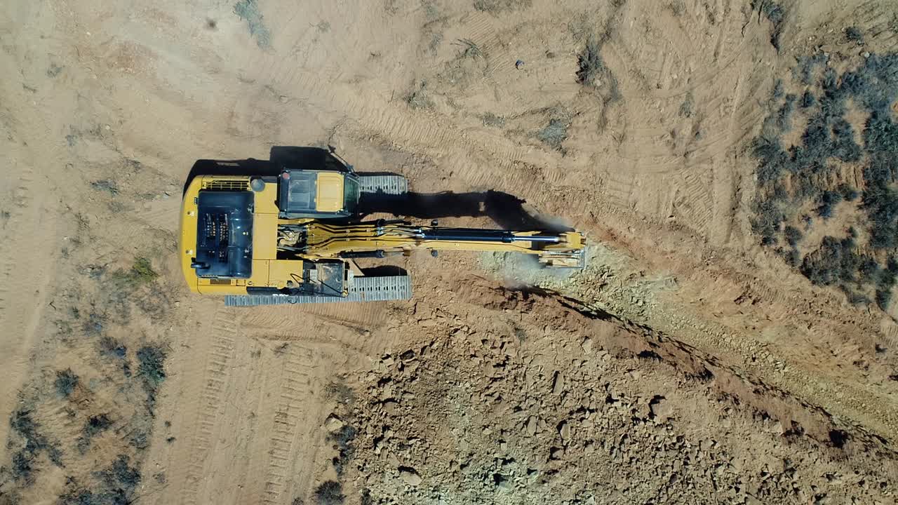 Overhead looks down on excavator equipment digging narrow trench