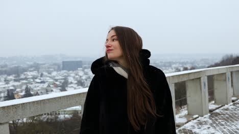 красивая женщина идет по смотровой площадке рядом с городом