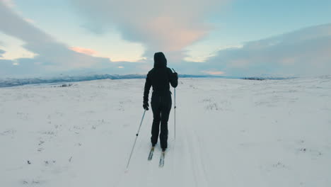 Camera-follows-a-female-cross-country-skier-on-a-ski-trail-on-a-snowy-mountain-in-the-northern-Sweden