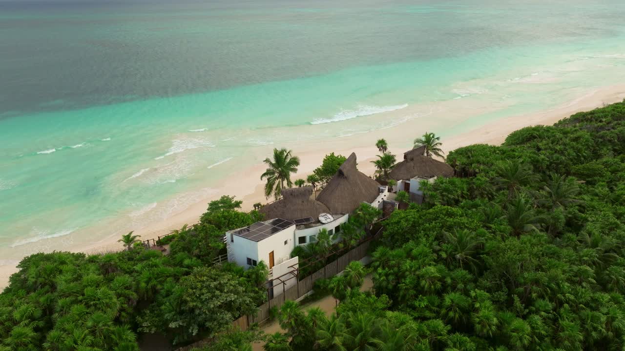 Resorts hiding along forested tropical beach in Tulum, Mexico, Aerial view