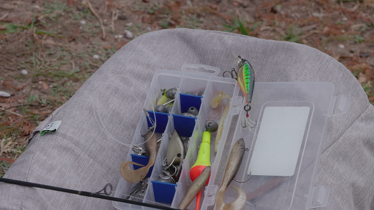 A close-up shot of a tackle box resting on top of a backpack, highlighting the vibrant colors and details of the tackle box. This composition reflects the anticipation of a day spent fishing