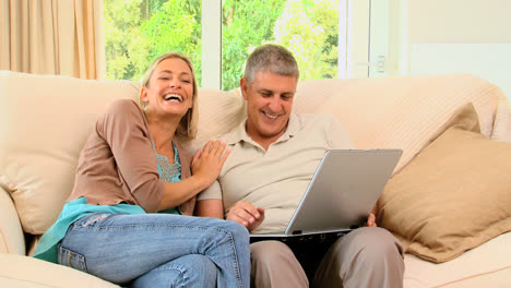 couple on sofa enjoying something on laptop