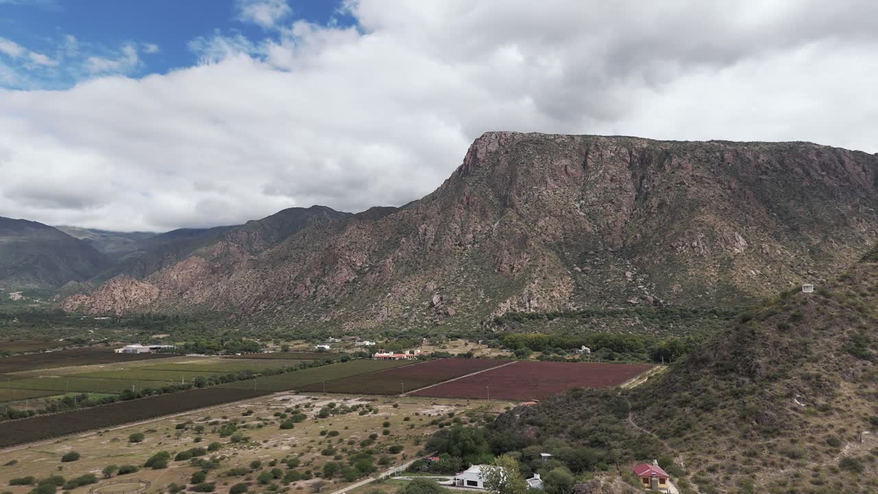 viñedos y campos bajo montañas escarpadas en cafayate, salta, argentina bajo un cielo nublado