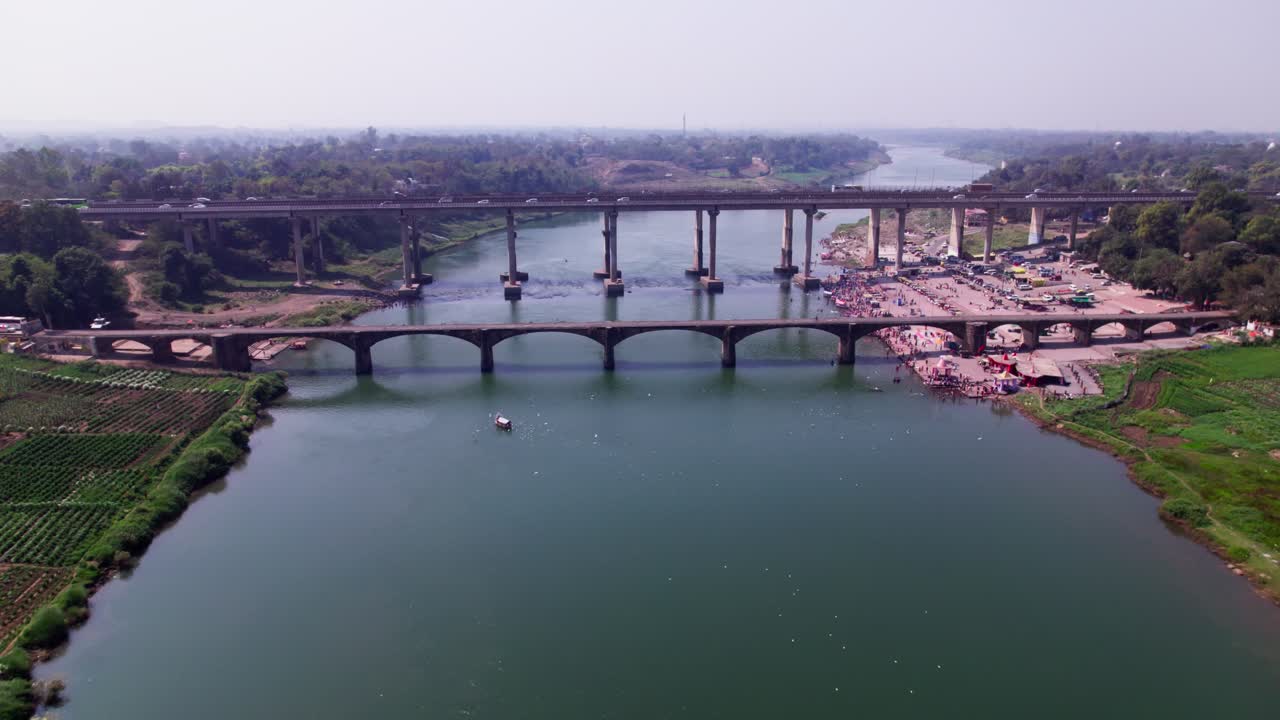 crop field lands with Tilwara Narmada River Bridge and flying birds at narmada ghat, tilwara, jabalpur, madhya pradesh, india. day time, push in, drone shot, 4k.