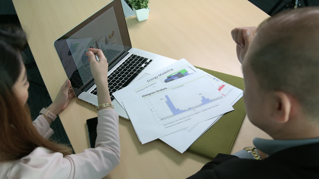Over The Shoulder Shot Of Asian Businesswoman Showing Presentation to A Businessman
