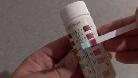 Man-shows-he-is-in-ketosis-with-a-keto-stick-and-bottle-with-keto-colours-displayed