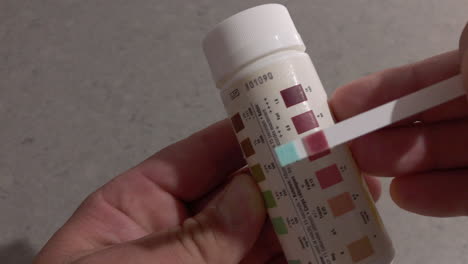 man shows he is in ketosis with a keto stick and bottle with keto colours displayed