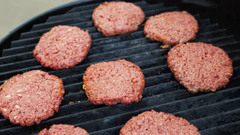 barbecuing plant based impossible burger patties on electric grill wide shot panning up showing 8 seasoned burgers freshly placed on the grill - in cinema 4k