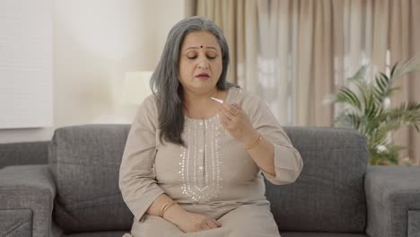 Sick-Indian-old-woman-checking-fever-using-thermometer