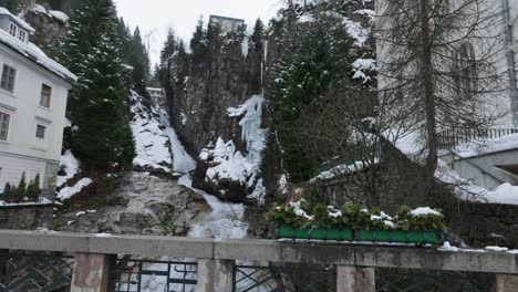 Cascada-Entre-Rocas-Y-Un-Antiguo-Pueblo-En-Invierno,-Cámara-Lenta