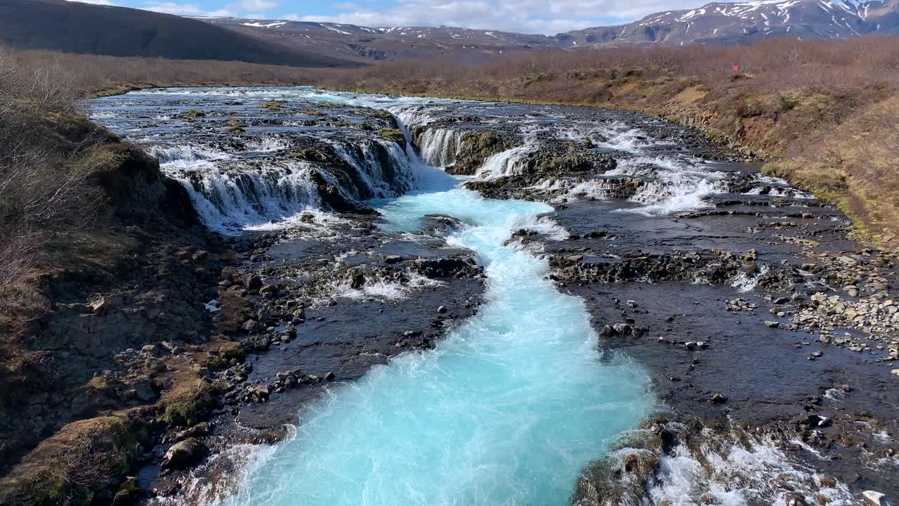 View over the beautiful waterfall Bruarfoss with Icelands most turquoise water, watching the water pouring from the rocks down in a stream and whirling around
