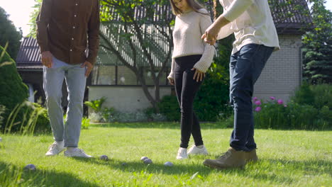 group of men and women friends approaching petanque balls in the park