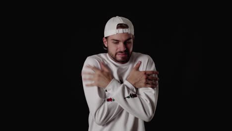 trendy 20s man freezing gesture, shaking and warming himself, wide, black background