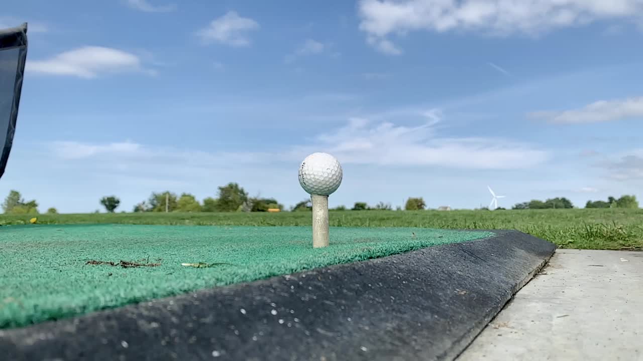 Close up of a golfer hitting the ball with a stick, in the golf club. Low angle, slow motion.