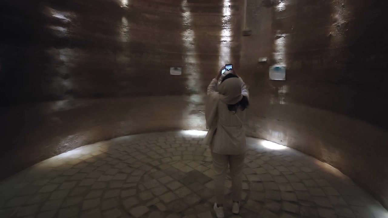 Donna che esplora e fotografa una storica camera sotterranea in pietra