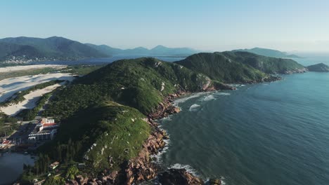 Beautiful-green-mountains-line-the-Brazilian-coastline-beside-the-famous-Joaquina-Beach,-creating-a-magical-setting-along-the-shores-of-the-Atlantic-Ocean