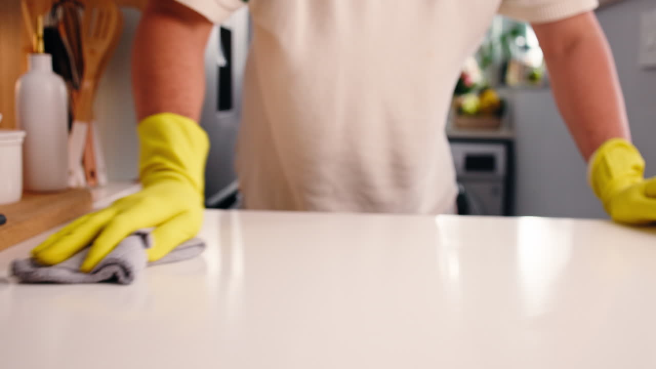 Persona con guanti gialli che pulisce il bancone della cucina