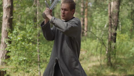 young man does sword strikes training for battle in wood