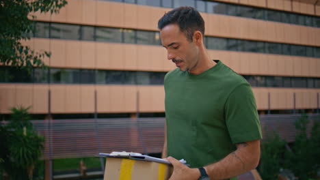 delivery guy calling mobile phone carrying parcel at modern street alone closeup