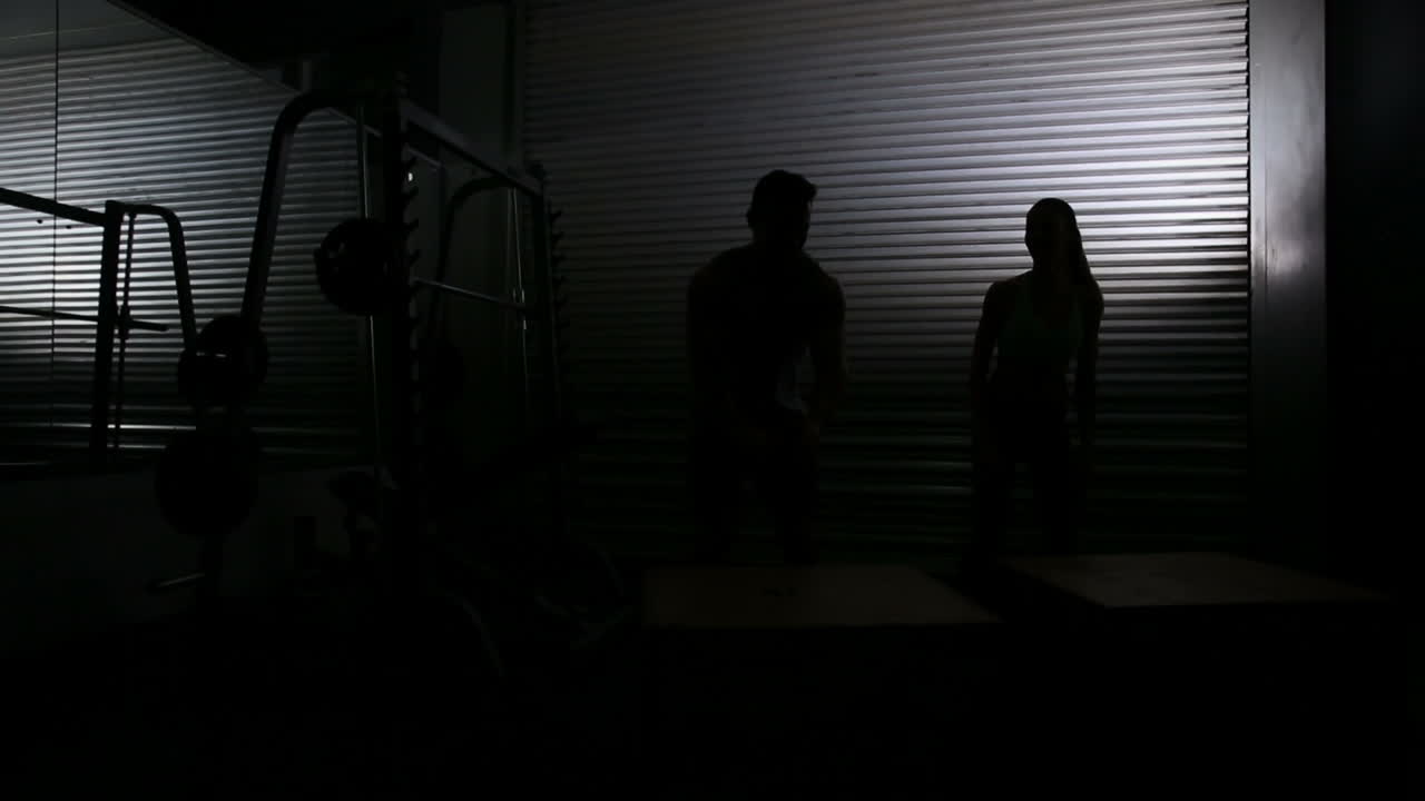 mujer en forma haciendo saltos de caja con el entrenador