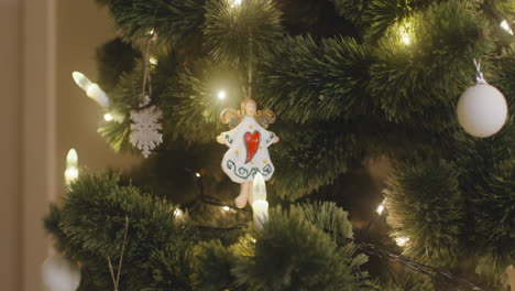 camera focuses on angel hanging on christmas tree with lights