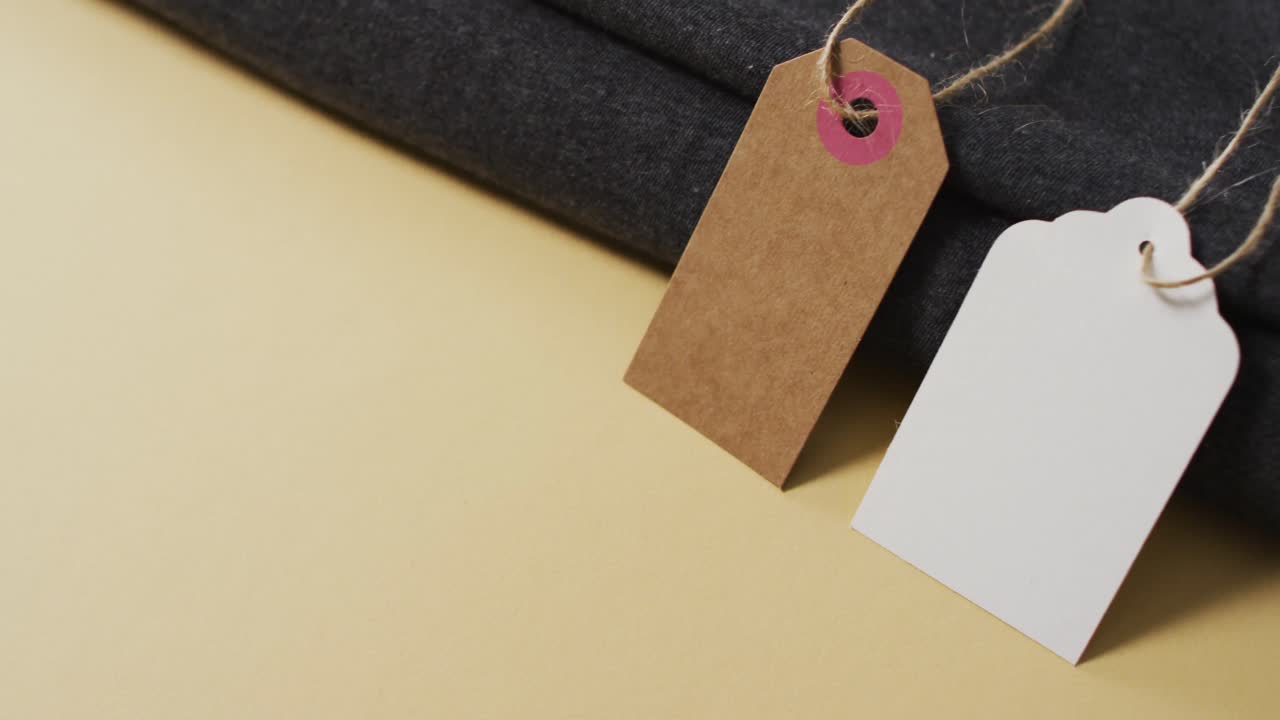 video di etichetta regalo bianca e marrone con corda e stoffa piegata su sfondo giallo