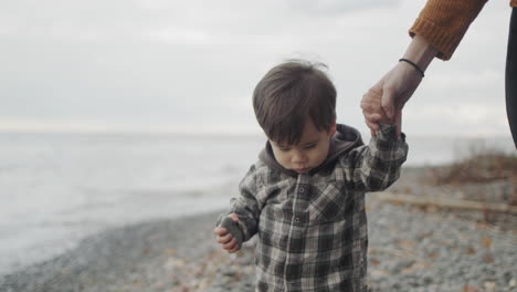 A-young-woman-leads-a-boy-by-the-hands-along-the-rocky-seashore