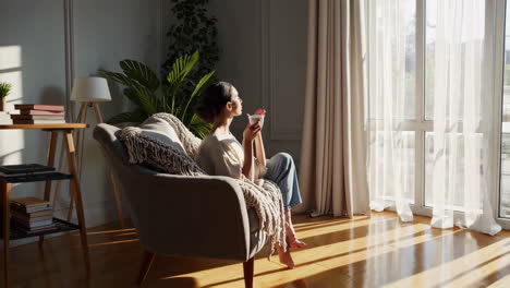 woman relaxing with a hot drink in sunlit armchair