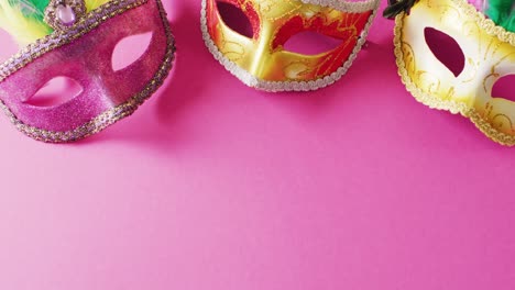 video of three pink and gold carnival masquerade masks on pink background with copy space