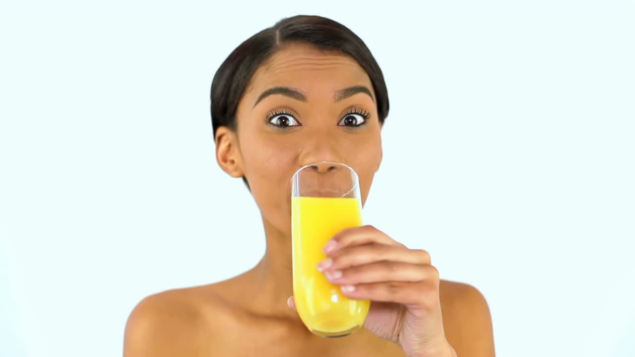 mujer bebiendo un vaso de jugo de naranja