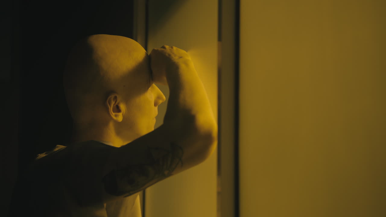 A bald man looks through the yellow glass