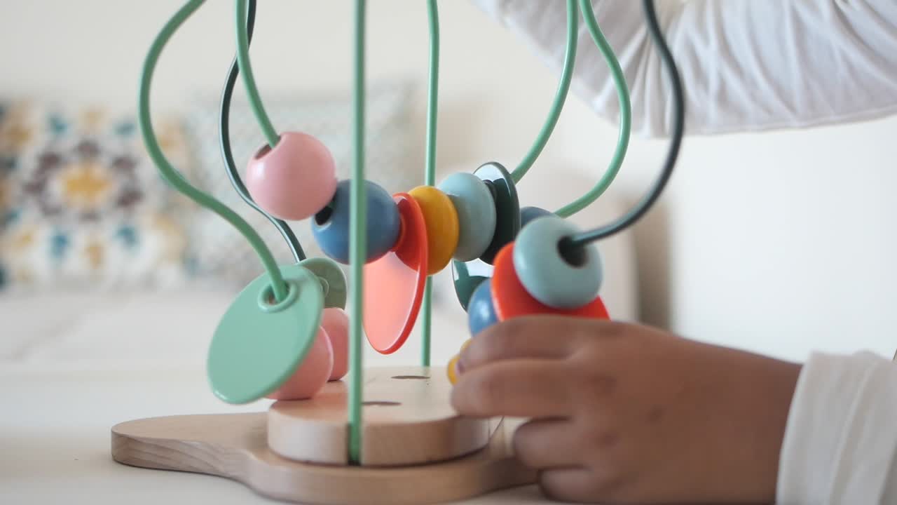 niño jugando con juguete de perlas de madera laberinto