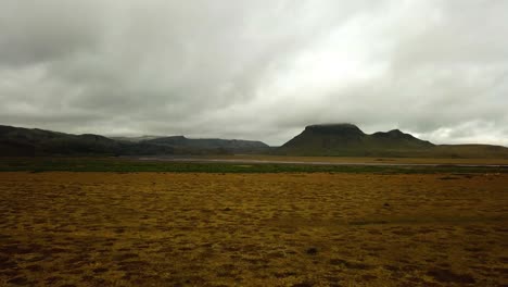 Aerial-landscape-view-of-a-glacier-river-with-flowing-in-a-valley,-on-dark-sand,-in-Iceland