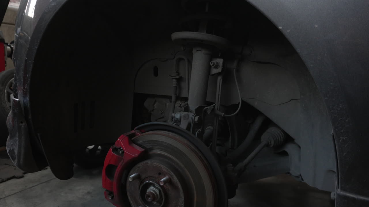 Close up of a vehicle brake system on a jack without wheels in a garage