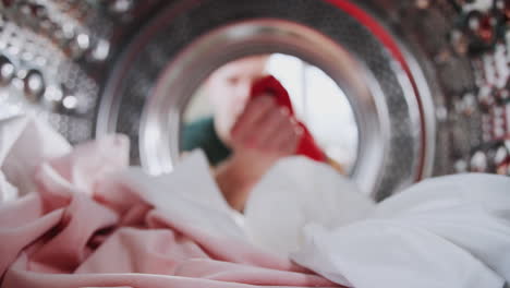 young man taking out red sock mixed with white laundry from washing machine