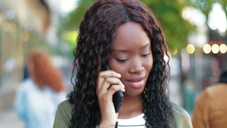 close-up view of african american woman talking on the phone while walking down the street