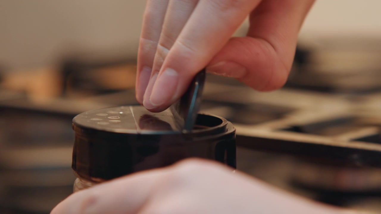 Hands expertly scoop and press spices. Closeup of hands skillfully managing spices with tools and care. Detailed depiction of hands accurately measuring and pressing spices with spoon and lid
