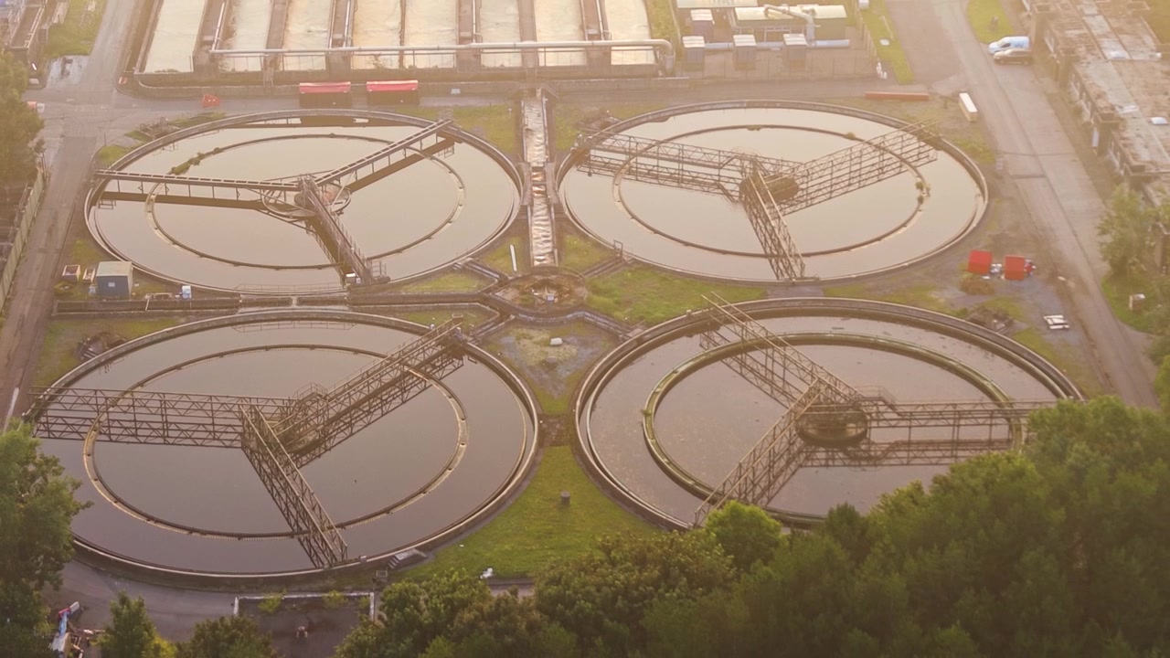 Close-up of Water Treatment Plant and wastewater recycling facility at sunrise. Golden Hour glow over Secondary Clarifiers. Clean tech, sustainability, and environmental engineering concept.