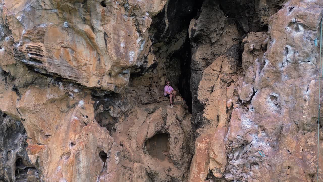 Rock climber resting during a difficult climb on Rai Leh beach cliff in Thailand. Nice aerial view flight pull in drone